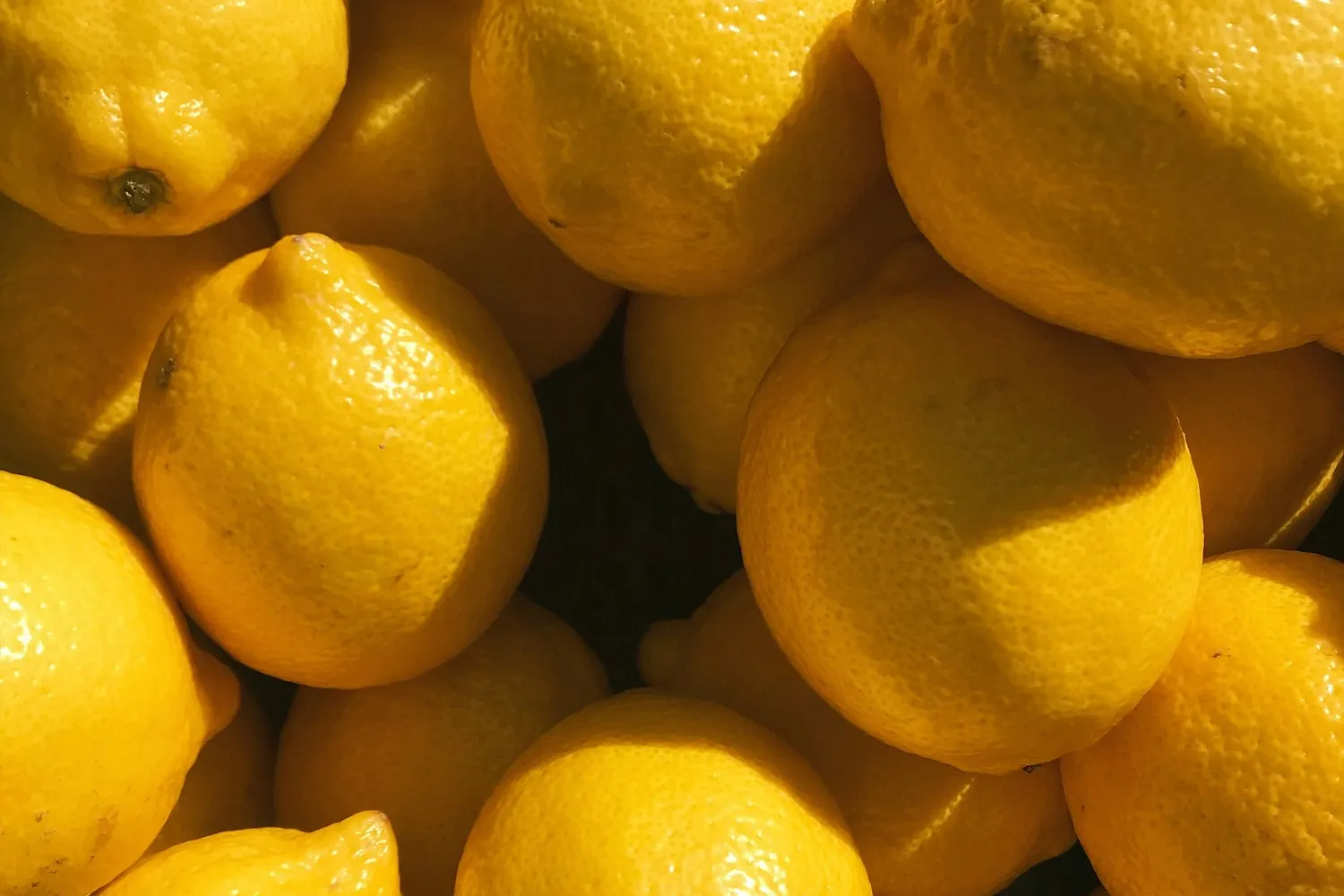 A pile of bright yellow lemons in warm sunlight